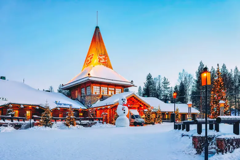 Snow-covered Santa Claus Village and its illuminated tower in Rovaniemi